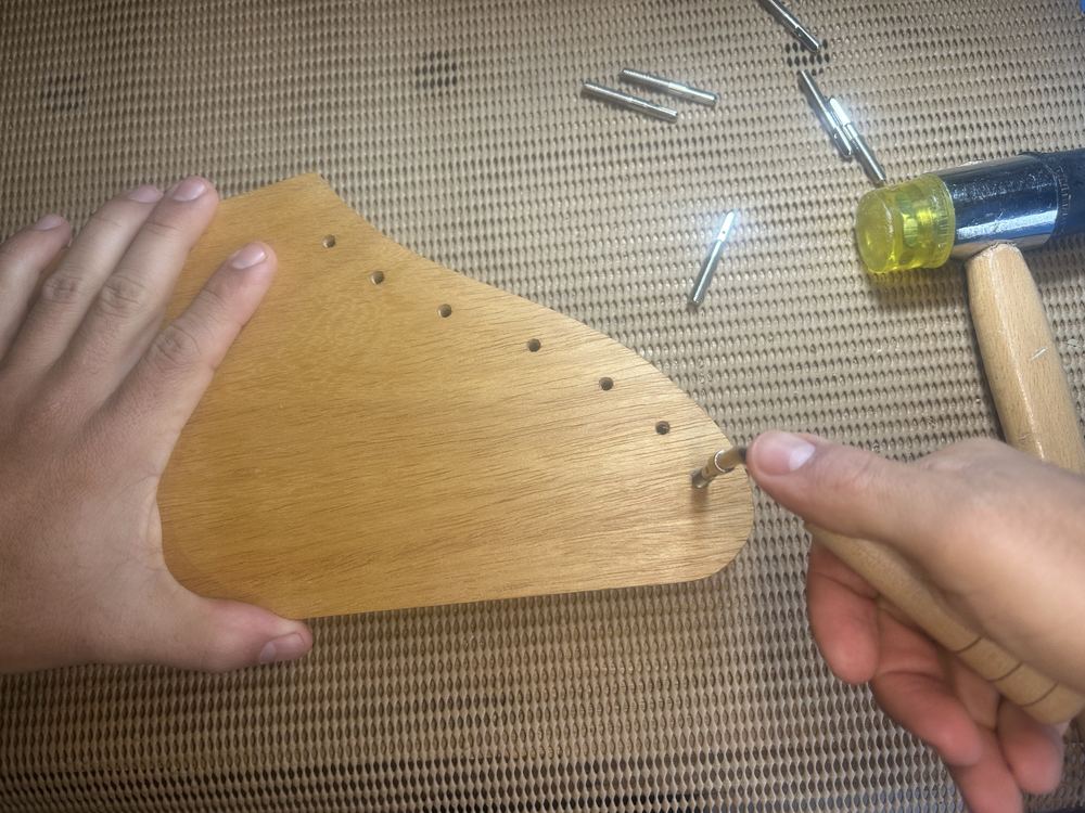 Com a chave de afinação, pressione o pino contra o furo e gire no sentido horário até o limite da rosca
